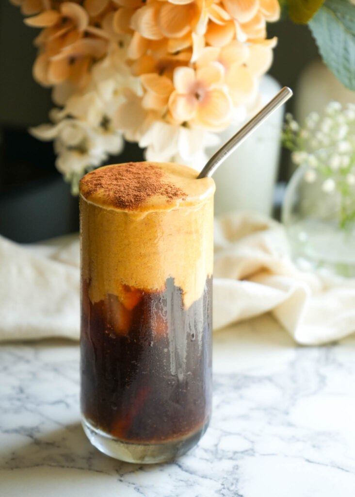 glass of cold brew topped with dairy free pumpkin cream cold foam