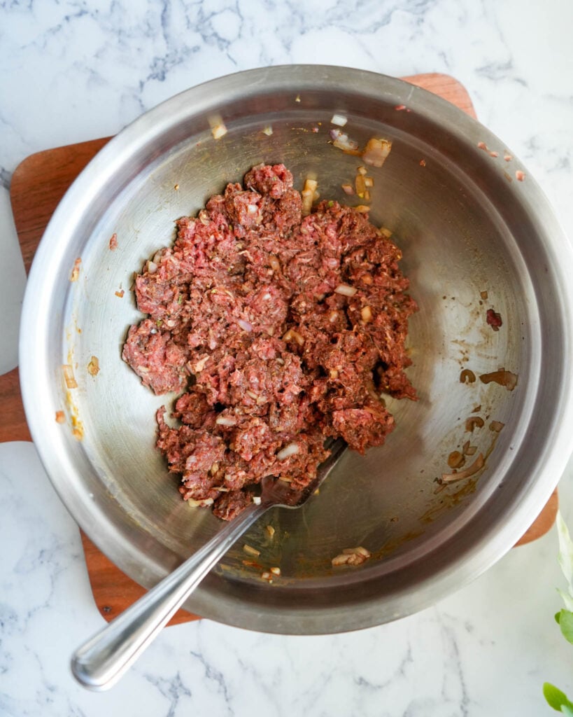 ground bison in a large mixing bowl with a fork