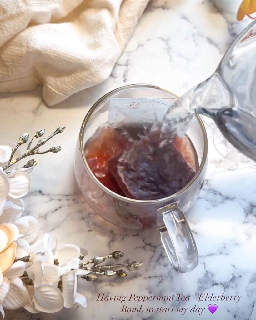 pouring hot water onto tea bag and elderberry bomb in a glass mug