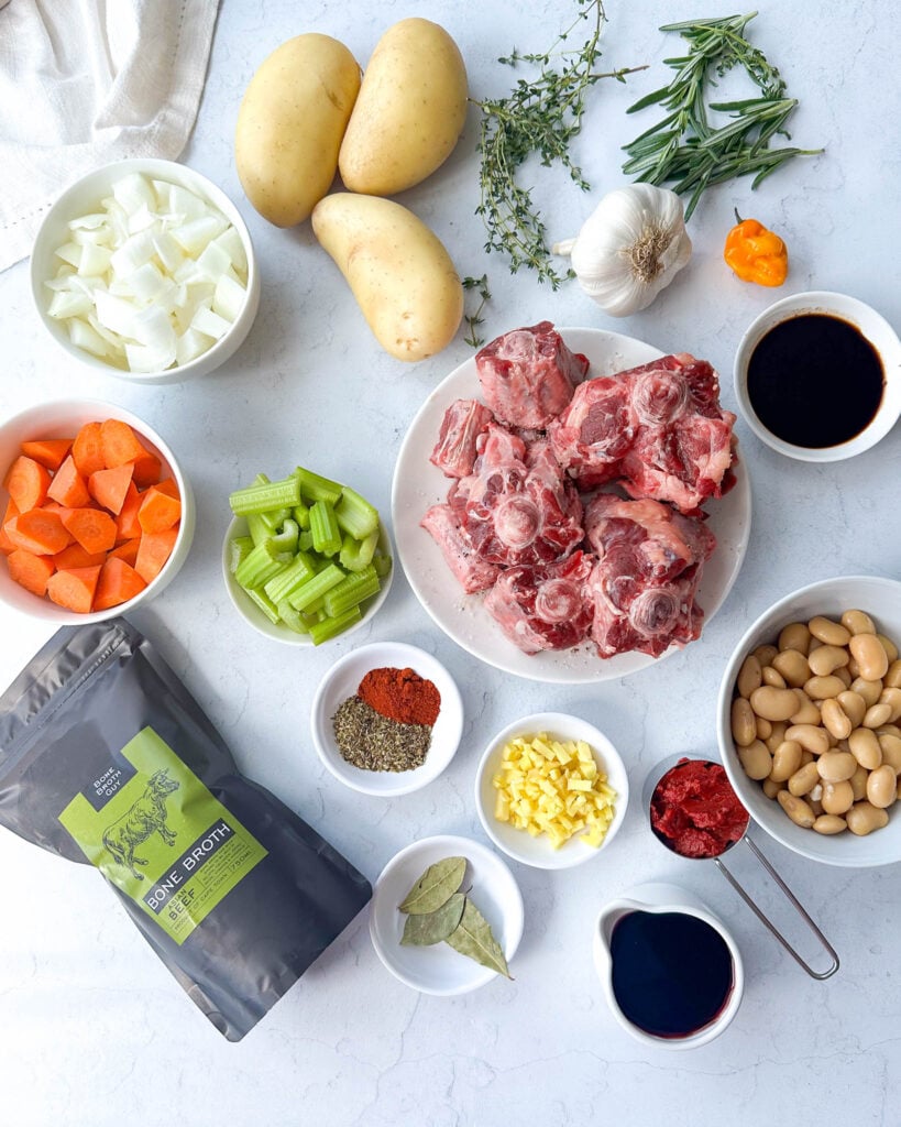 raw oxtail on a plate surrounded by ingredients to make oxtail stew