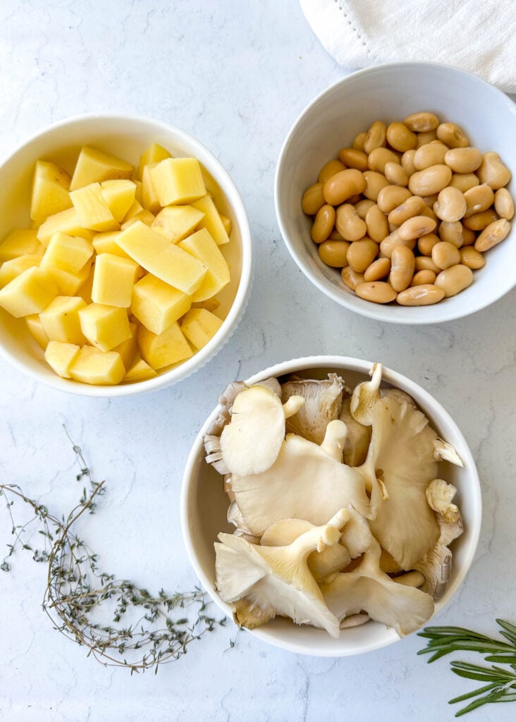 a small bowl of potatoes a small bowl of butter beans a small bowl of oyster mushrooms