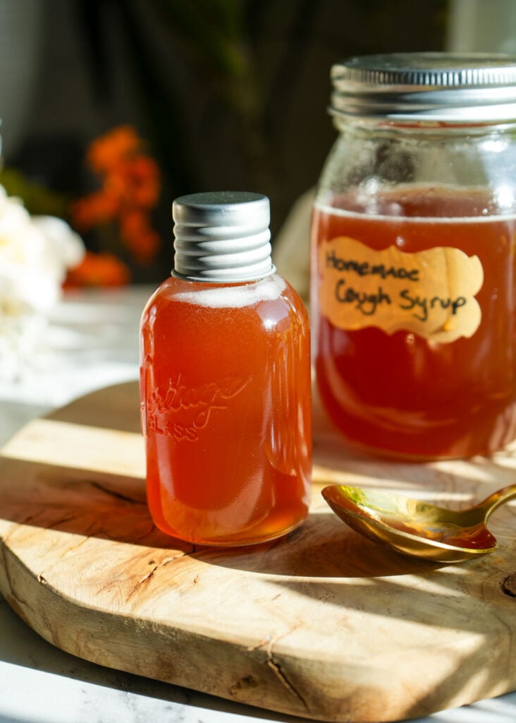 a small 2 ounce mason jar of homemade cough syrup and a larger jar in the background