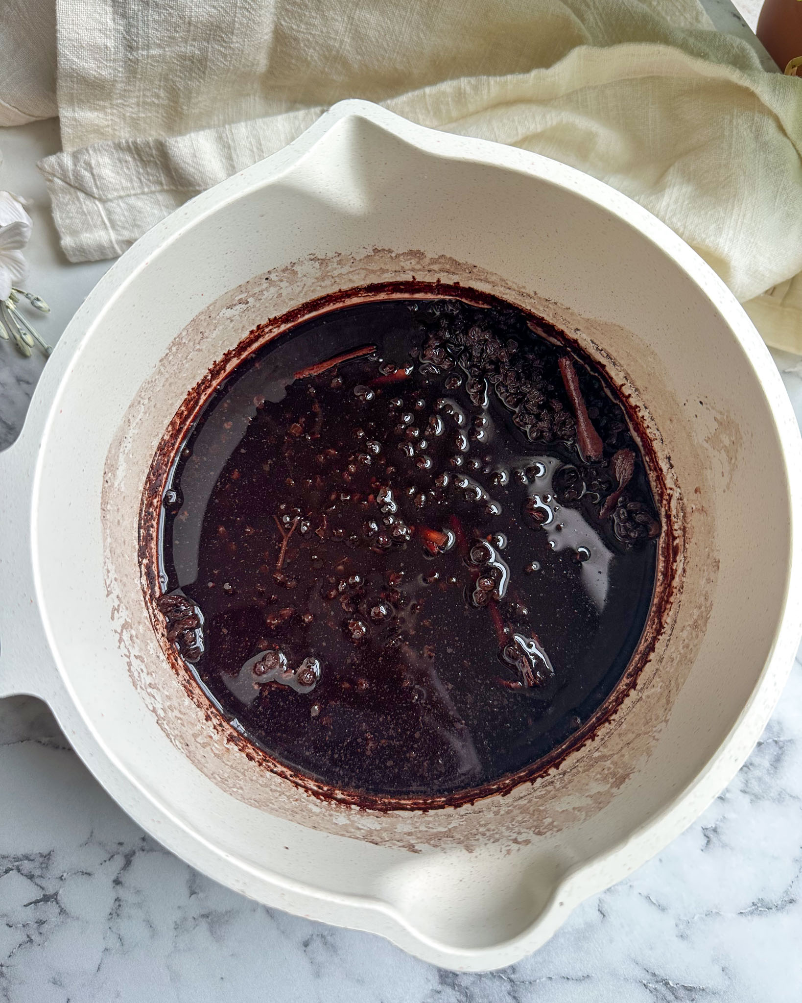 A pot showing reduced elderberry syrup after simmering with cinnamon and spices.