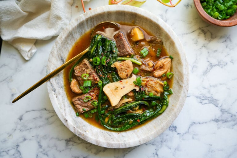 ginger beef soup in a marble bowl with a golden spoon