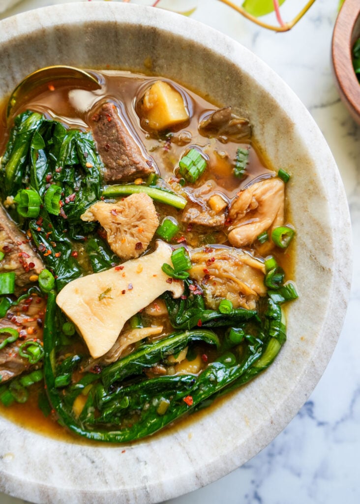 ginger beef soup in a marble bowl with a golden spoon