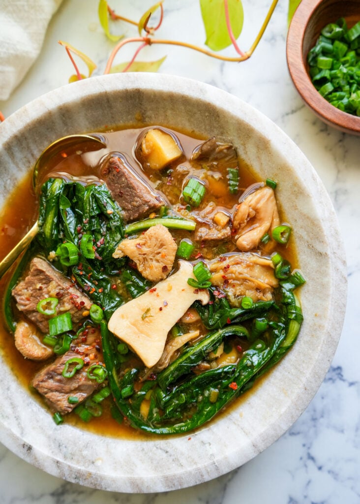 ginger beef soup in a marble bowl with a golden spoon