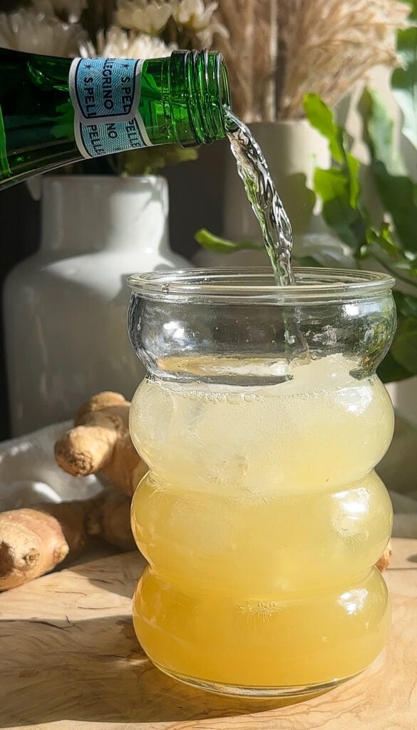 pouring sparkling water into ginger mixture to make ginger ale