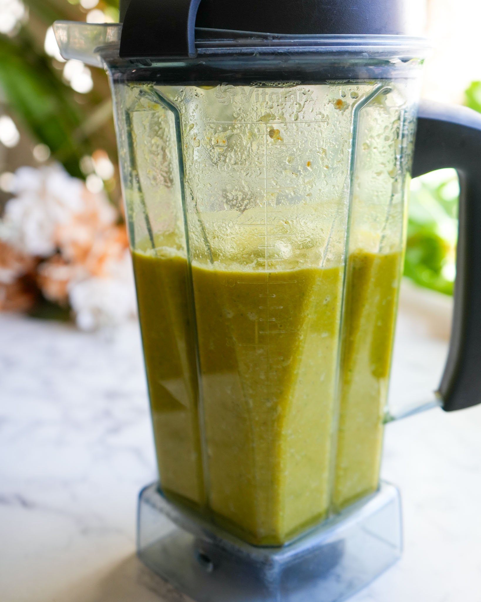 A blender filled with a smooth, bright yellow mixture of blended fire cider ingredients, ready for straining.