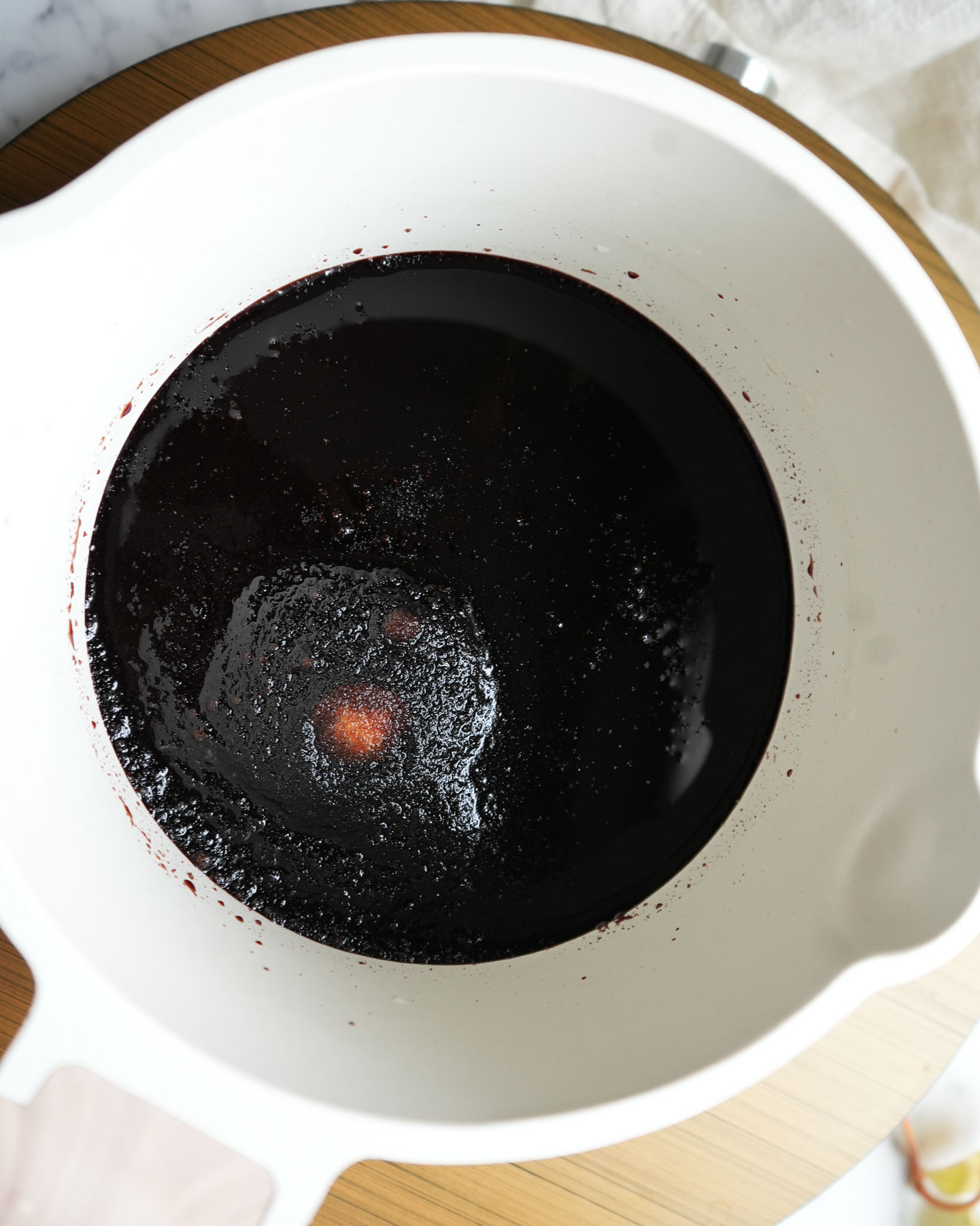 A close-up of a pot with thickened elderberry syrup after cooking.