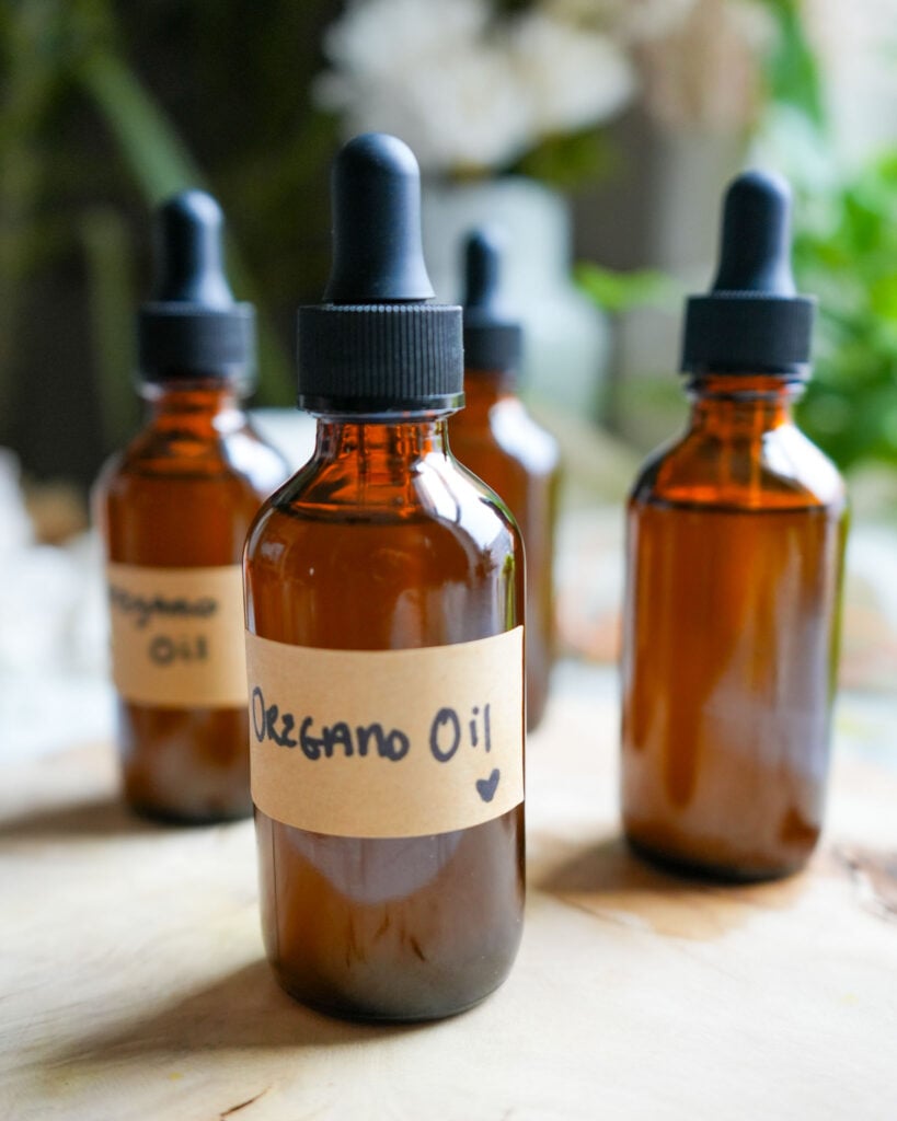 Three amber glass bottles of oregano oil on a wooden surface.