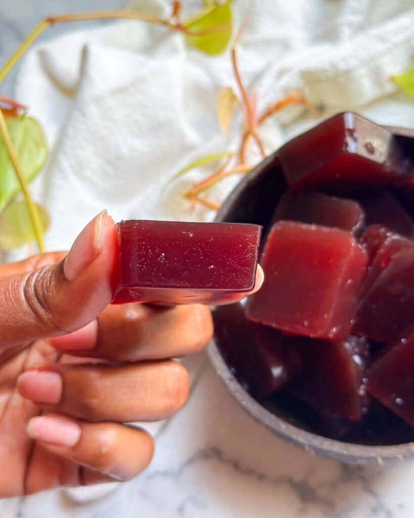 homemade collagen gummies in a bowl holding one close to camera to show texture and size