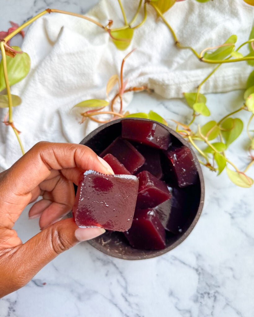 homemade collagen gummies in a bowl holding one close to camera to show texture and size