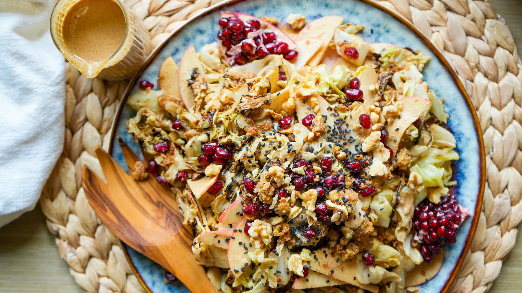 roasted cabbage salad with maple tahini dressing sliced apples pomegranate and crispy quinoa on a plate