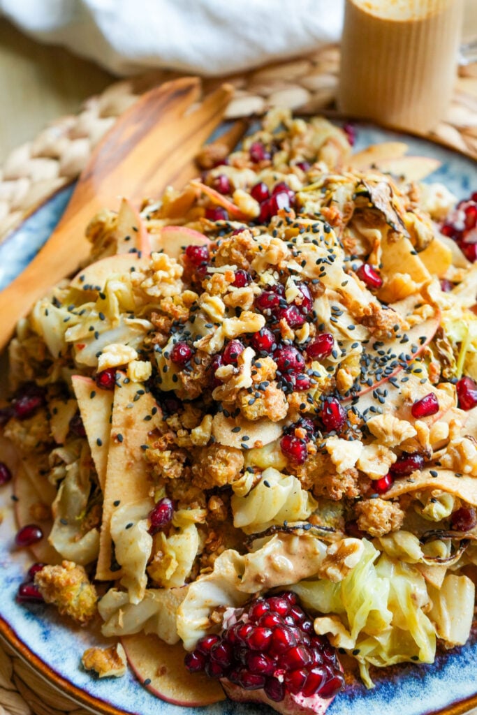 roasted cabbage salad with maple tahini dressing sliced apples pomegranate and crispy quinoa on a plate