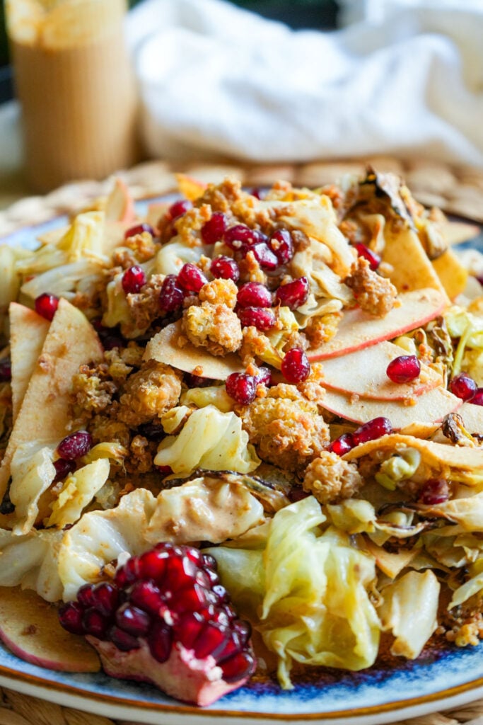 roasted cabbage salad with maple tahini dressing sliced apples pomegranate and crispy quinoa on a plate