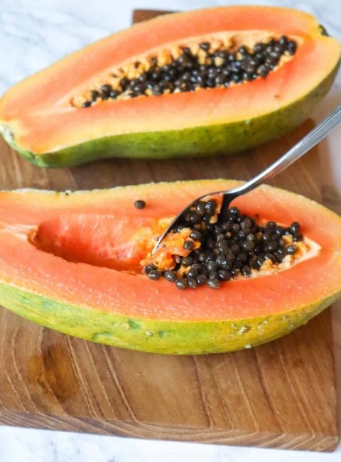 showing how to prepare papaya by scooping out seeds in the middle