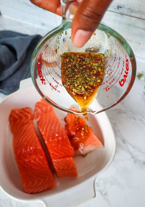 A mixture of maple, soy and ginger being poured over raw salmon.